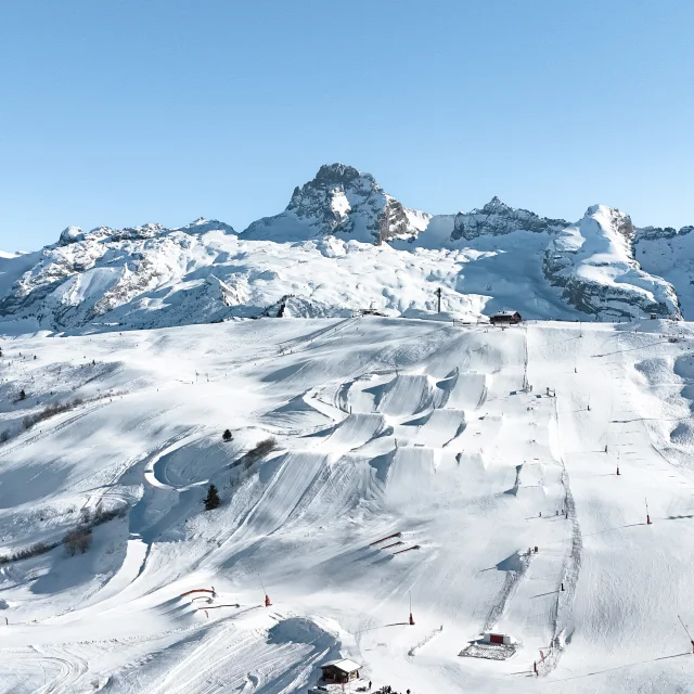 Une vue aérienne du snowpark du grand bornand et ses 6 hectares d'infrastructures freestyle avec la pointe percéeen arrière plan