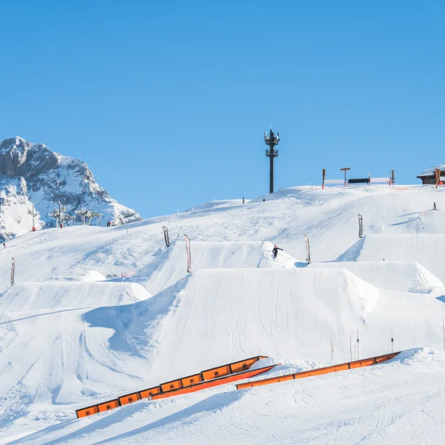 Les réceptions des ligne L et XL du snowpark du grand-bornand avec en arrière plan la pointe percée ainsi que le restaurant des terres rouges. En premier plan se trouve des barres de slide