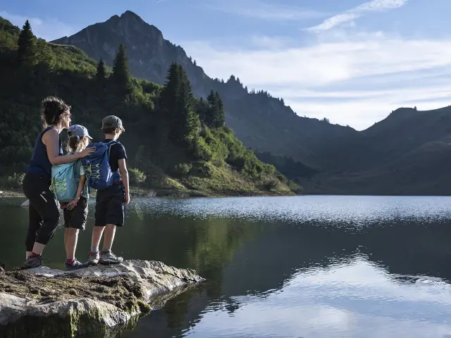 Une mère et ses deux enfants regardent avec émerveillement le lac de Lessy en été