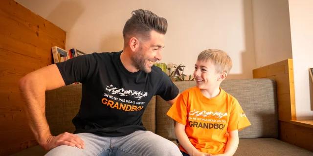 Un homme avec un petit garçon qui portent tous les 2 un tee-shirt en vente à la boutique de l'Office de tourisme