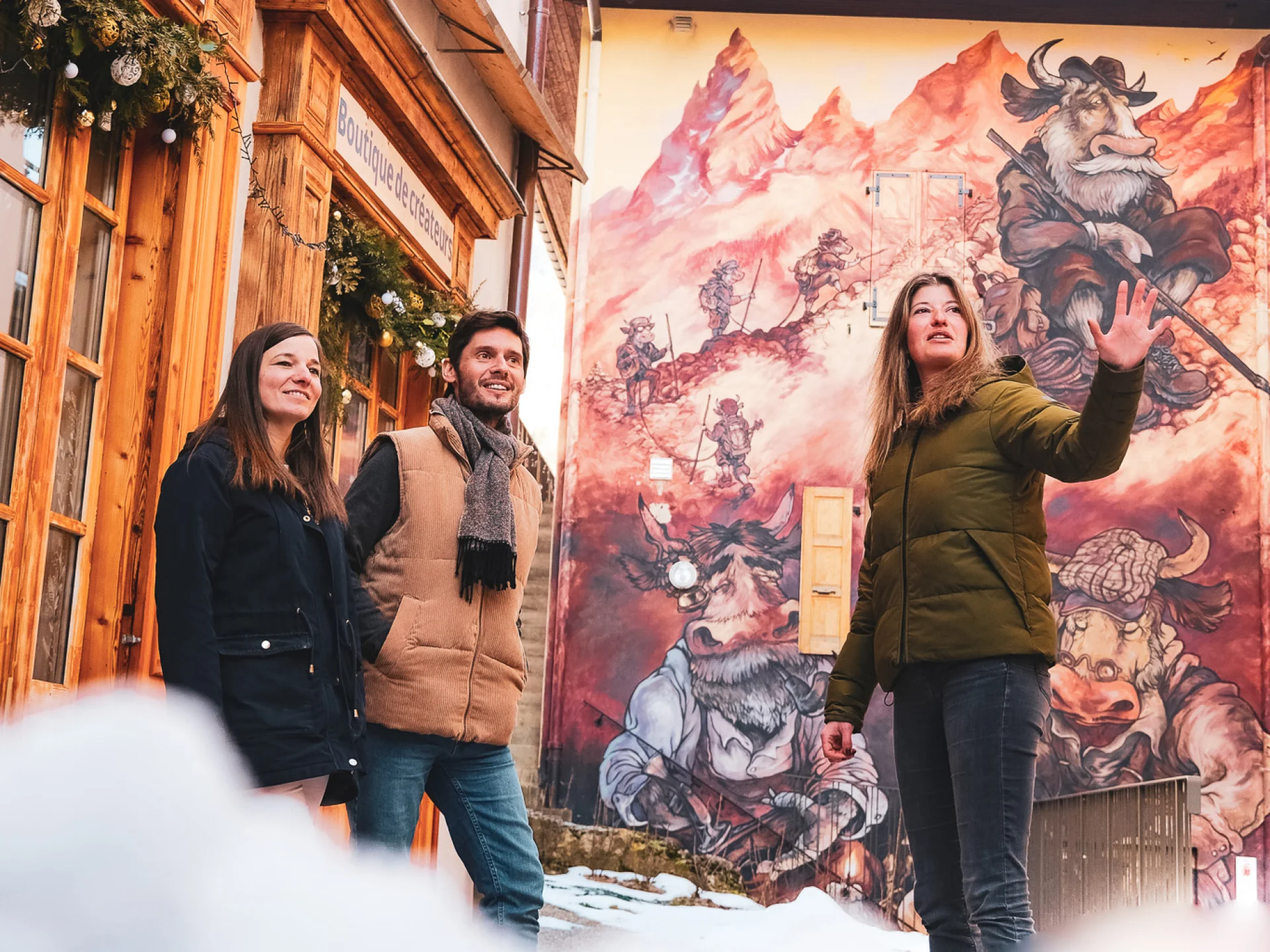 Deux personnes participent à une visite guidée du Village, et se trouvent devant une création du parcours de l'Art Vache, en plein hiver