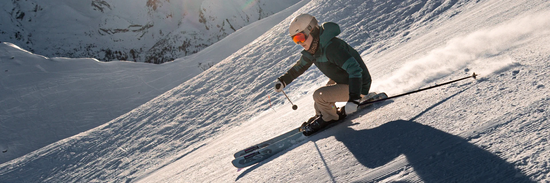 Une skieuse alpine dévalant une piste avec pour toile de fond, la chaîne des Aravis