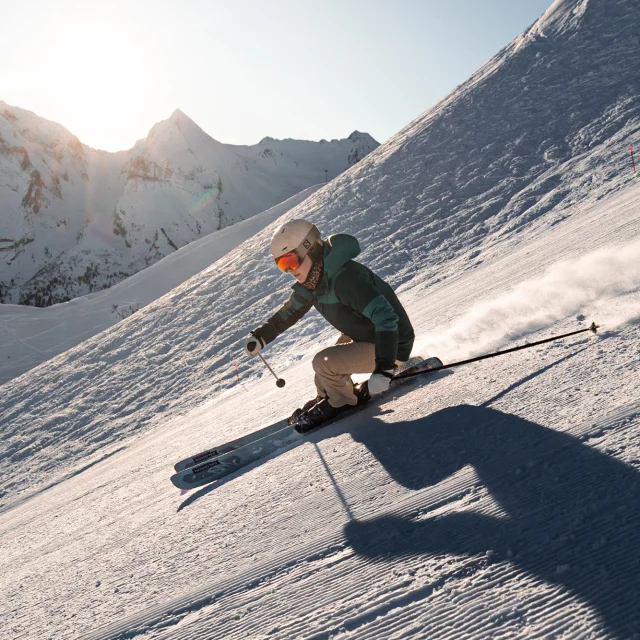 Une skieuse alpine dévalant une piste avec pour toile de fond, la chaîne des Aravis