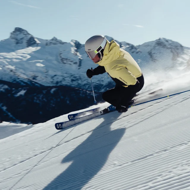Skieur alpin dévalant la piste 2000 avec comme toile de fond, la chaîne des Aravis et la pointe Percée