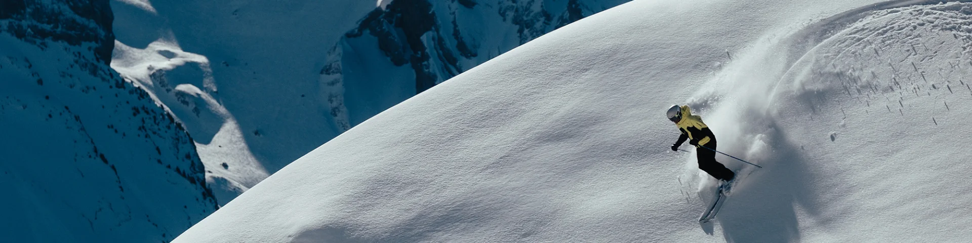 Skieur alpin faisant les premières traces dans un décors enneigé, avec pour toile de fond, la chaîne des Aravis