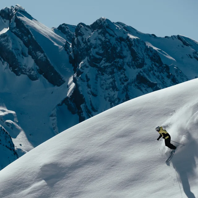 Skieur alpin faisant les premières traces dans un décors enneigé, avec pour toile de fond, la chaîne des Aravis