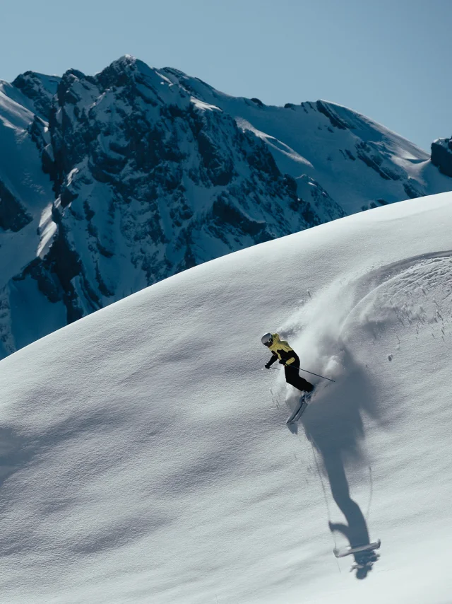 Skieur alpin faisant les premières traces dans un décors enneigé, avec pour toile de fond, la chaîne des Aravis