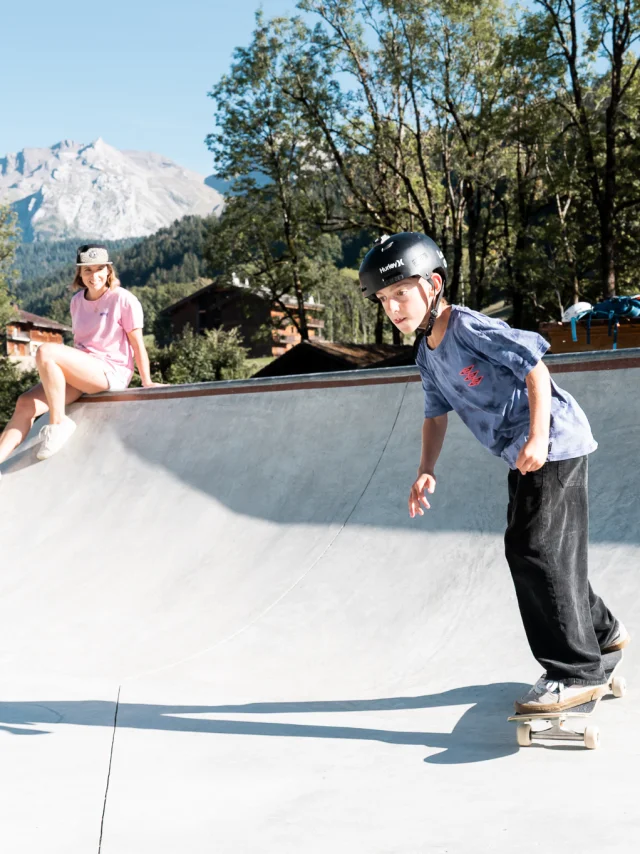 Un enfant fait du skate sur le nouveau skatepark du Grand-Bornand, sa mère, assise au bord, le regarde