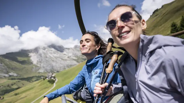Deux amis, en éclat de rire, prennent les remontées mécaniques en été pour arriver en haut du mont Lachat