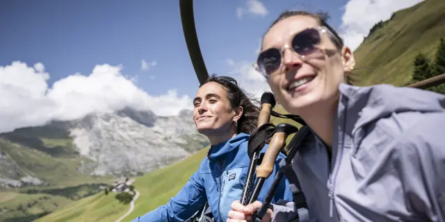 Deux amis, en éclat de rire, prennent les remontées mécaniques en été pour arriver en haut du mont Lachat