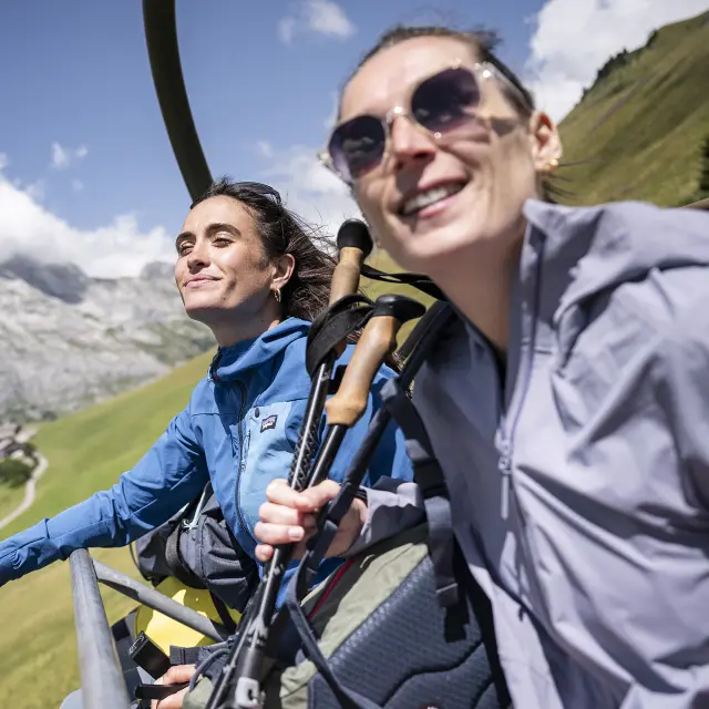 Deux amis, en éclat de rire, prennent les remontées mécaniques en été pour arriver en haut du mont Lachat
