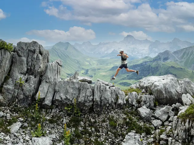 Randonneur faisant l'ascension du Jallouvre, saute d'un cailloux à l'autre avec comme toile de fond, la pointe Percée