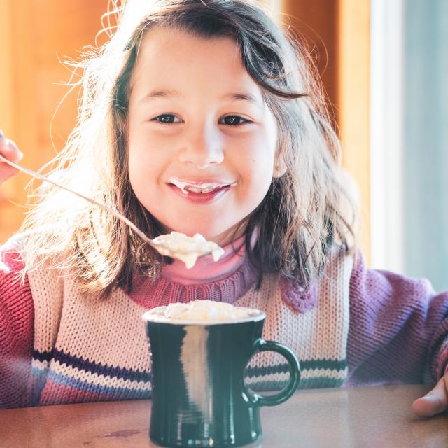 Jeune fille profitant de son chocolat chaud dans un restaurant de altitude de la station de ski Les Deux Alpes