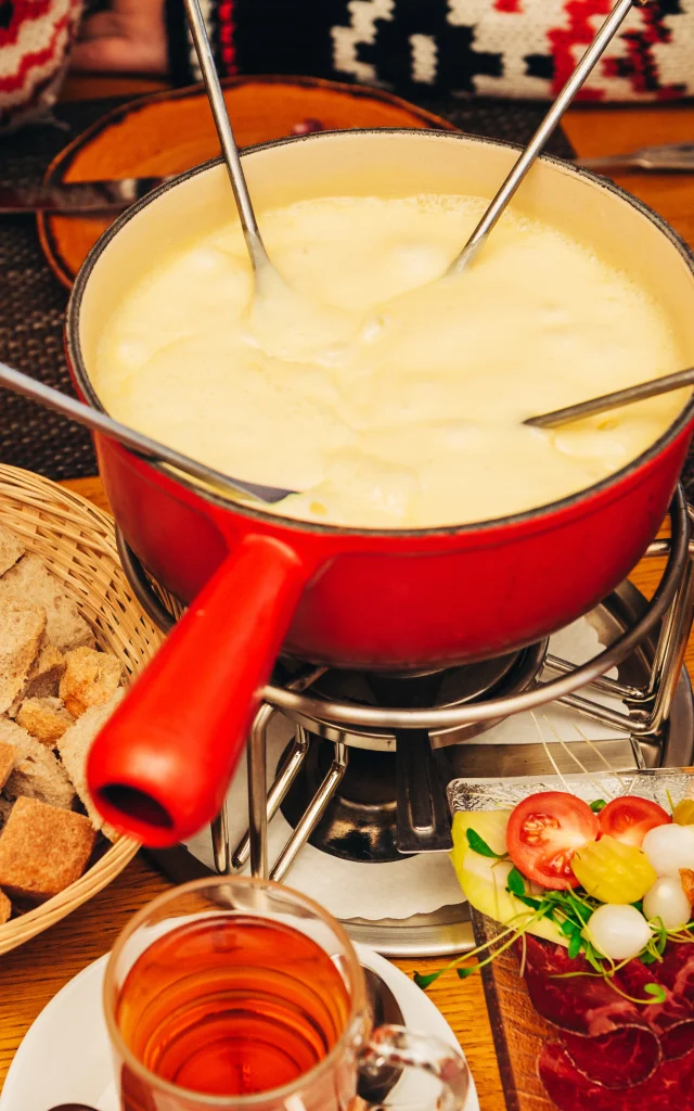 Friends eating cheese fondue in a cozy traditional swiss restaurant