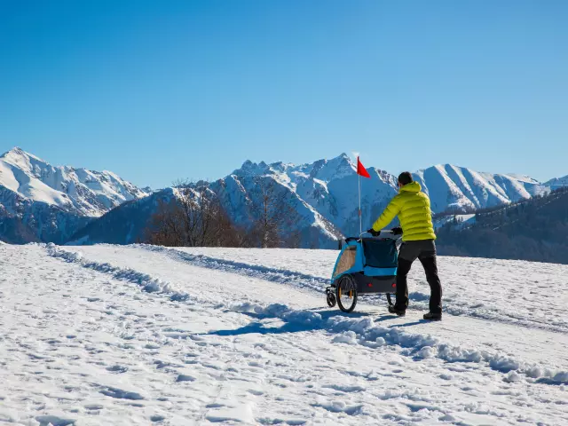 Escursionista in montagna che spinge un passeggino nella neve