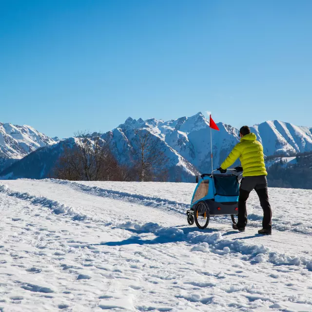 Hiker in the mountains pushing a stroller in the snow