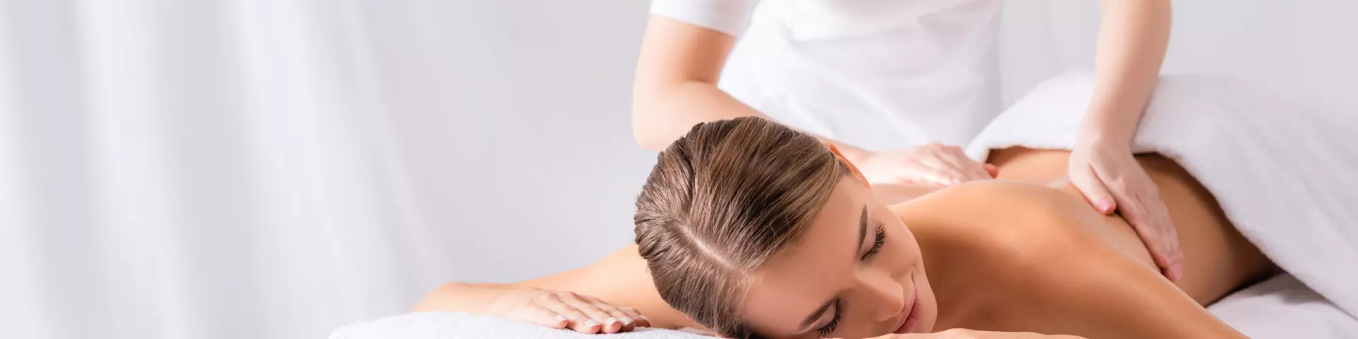 masseur massaging pleased young woman on massage table in spa salon, banner