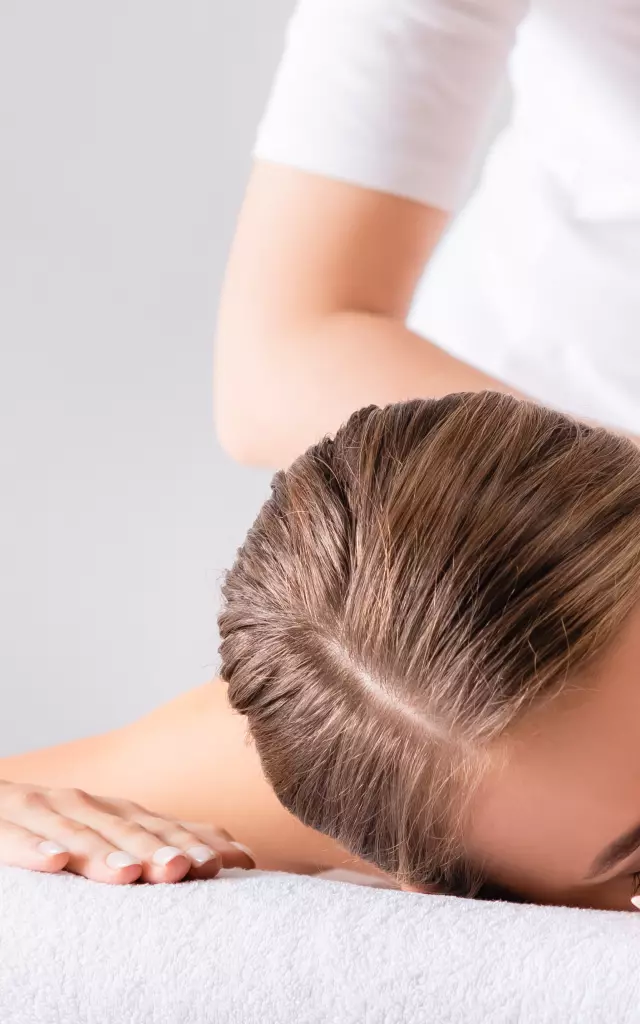 masseur massaging pleased young woman on massage table in spa salon, banner