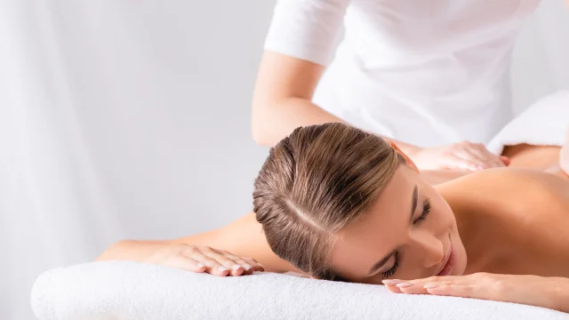 masseur massaging pleased young woman on massage table in spa salon, banner