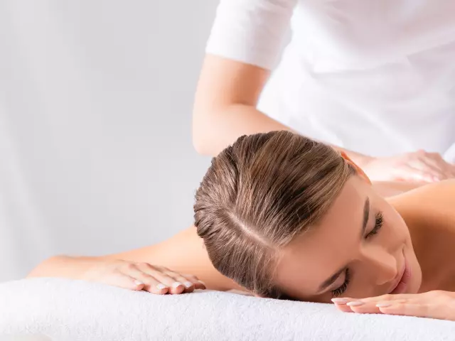 masseur massaging pleased young woman on massage table in spa salon, banner