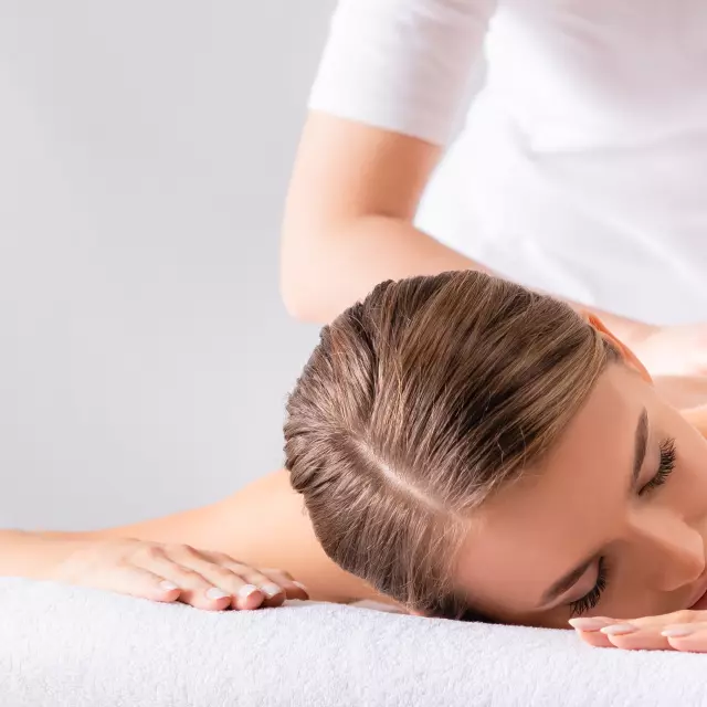 masseur massaging pleased young woman on massage table in spa salon, banner