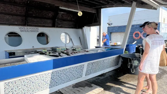 Deux personnes sont devant un stand sur le marché aux poissons de Port Leucate.