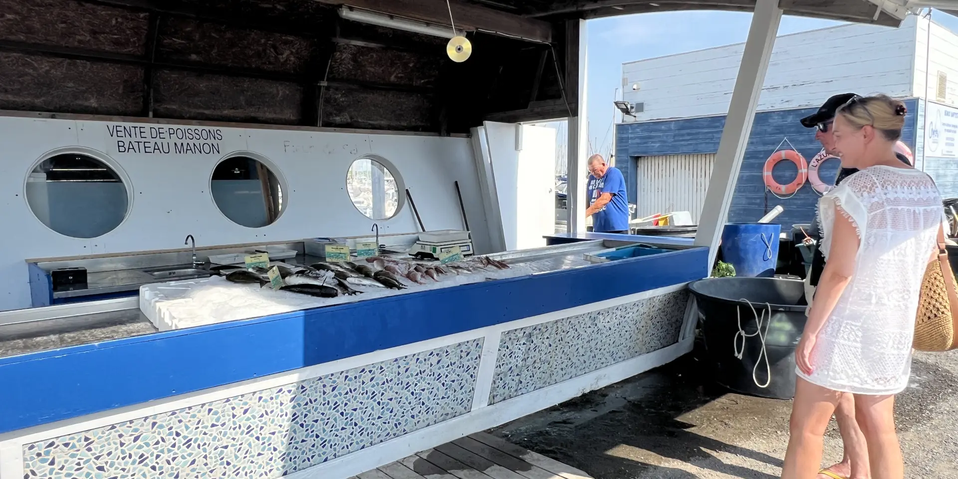 Deux personnes sont devant un stand sur le marché aux poissons de Port Leucate.