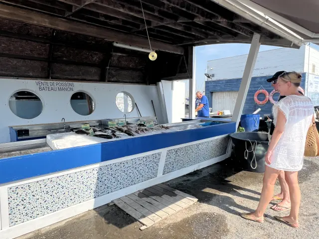 Deux personnes sont devant un stand sur le marché aux poissons de Port Leucate.