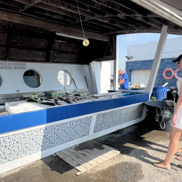 Deux personnes sont devant un stand sur le marché aux poissons de Port Leucate.