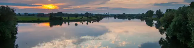 Coucher de soleil sur la confluence de la Deûle et de la Lys, reflets paisibles dans l’eau entourée de nature, au cœur de la métropole lilloise.