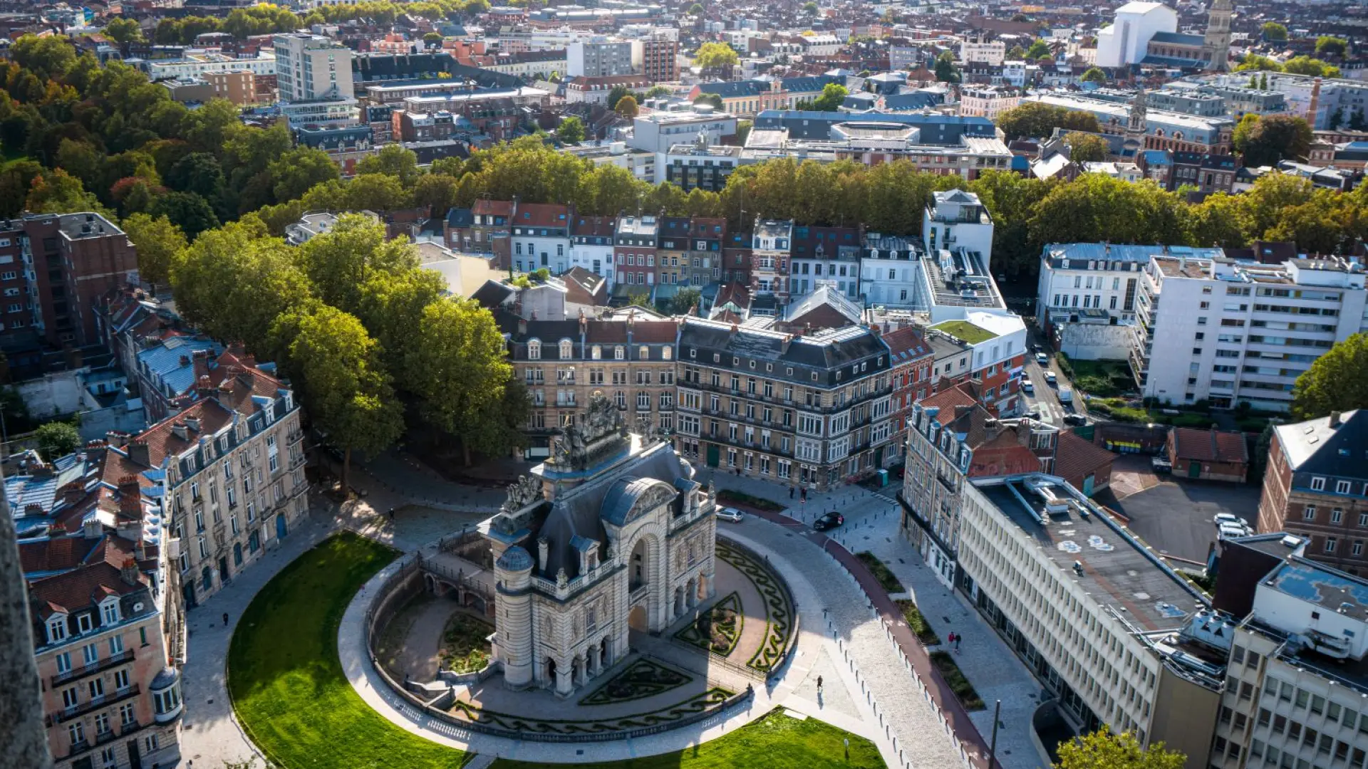 Aerial view of the Porte de Paris in Lille, surrounded by Haussmann-style buildings and green spaces, taken from the belfry of the Hôtel de Ville.