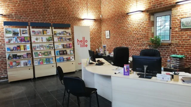 Accueil de l’antenne de l’Office de Tourisme à Villeneuve d’Ascq, avec comptoir d’information, rayonnages de brochures et mur en briques rouges.