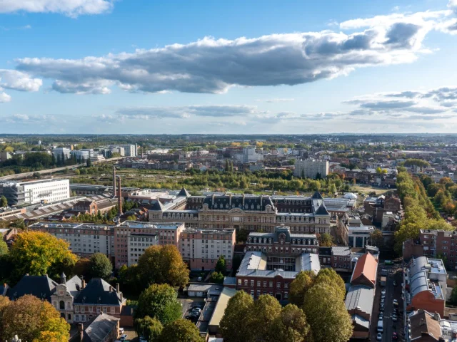 Vue plongeante sur l’École nationale des arts et métiers de Lille, entourée de verdure et de quartiers résidentiels, sous un ciel partiellement nuageux.