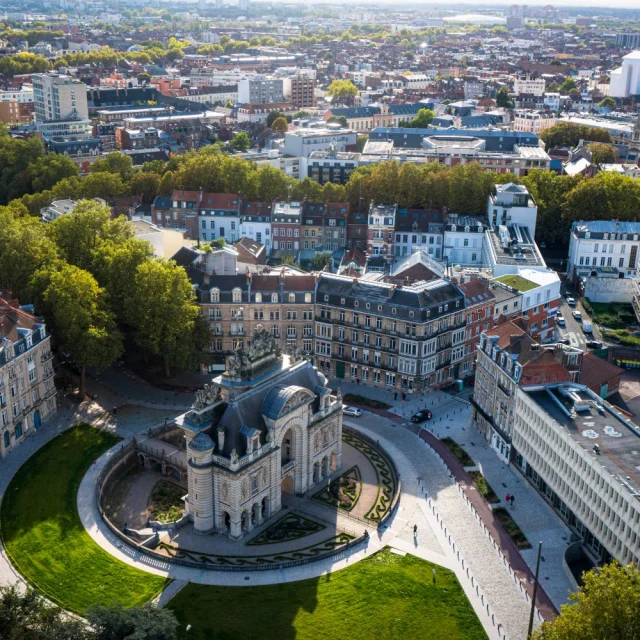Vue aérienne de la Porte de Paris à Lille, entourée de bâtiments haussmanniens et d’espaces verts, prise depuis le beffroi de l’Hôtel de Ville.