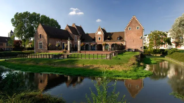 Château de Flers à Villeneuve-d’Ascq, bâtiment en briques rouges bordé de douves et de pelouses verdoyantes.