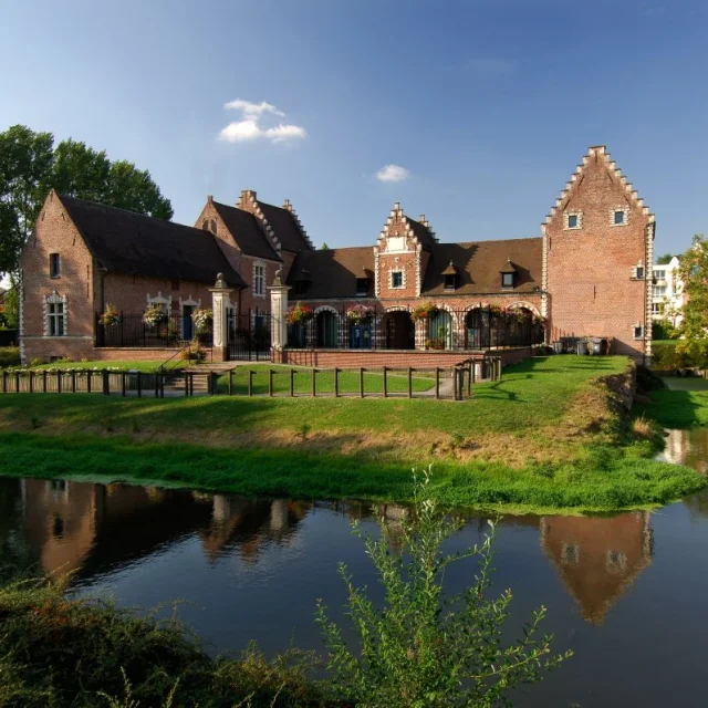 Château de Flers à Villeneuve-d’Ascq, bâtiment en briques rouges bordé de douves et de pelouses verdoyantes.