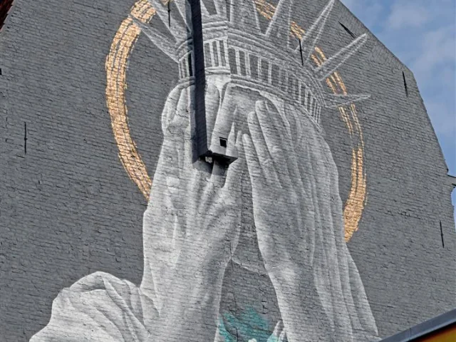 Oeuvre street-art représentant la statue de la Liberté se cachant les yeux pour ne pas voir les horreurs qui se déroulent dans le Monde.