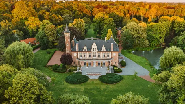 Vue aérienne du château de la Fontaine à Croix, entouré de vastes jardins arborés et d’un plan d’eau, en fin de journée.