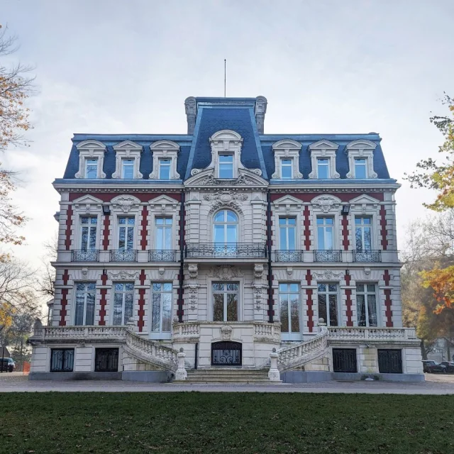 Façade symétrique de l’hôtel de ville de Croix, élégante bâtisse de style néo-Renaissance en pierre et brique, bordée d’arbres aux teintes automnales.