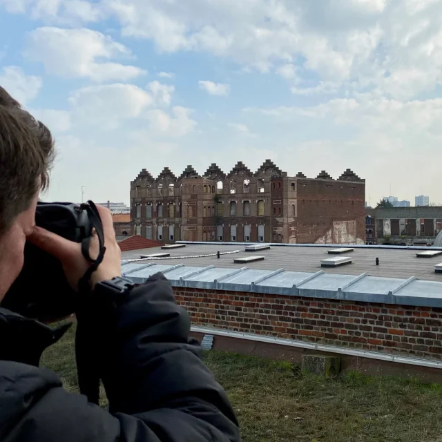 Photographe cadrant une façade en ruine en briques rouges à Roubaix, symbole du passé industriel de la ville.