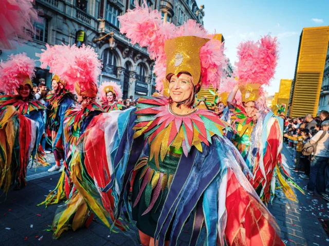Danseuses en costumes multicolores et coiffes à plumes roses défilant lors de la 7ᵉ édition de la parade Fiesta lille3000.