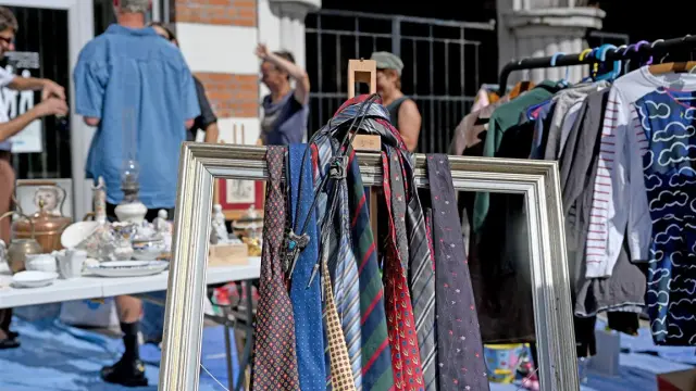 Stand de la Braderie de Lille avec cravates suspendues dans un cadre, vaisselle ancienne et ambiance conviviale entre chineurs.