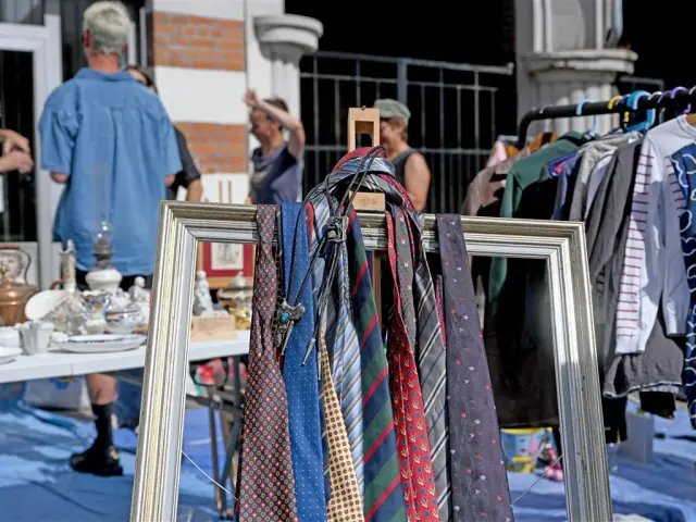 Stand de la Braderie de Lille avec cravates suspendues dans un cadre, vaisselle ancienne et ambiance conviviale entre chineurs.