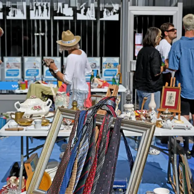 Stand de la Braderie de Lille avec cravates suspendues dans un cadre, vaisselle ancienne et ambiance conviviale entre chineurs.