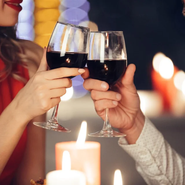 Close-up van jong stel dat glazen met rode wijn vasthoudt terwijl ze romantisch dineren S