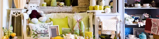 Boutique déco chaleureuse avec vaisselle, coussins et objets aux tons verts et jaunes.