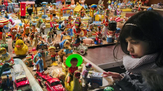Enfant découvrant un stand de jouets anciens en métal coloré sur le marché de Noël de Lille.