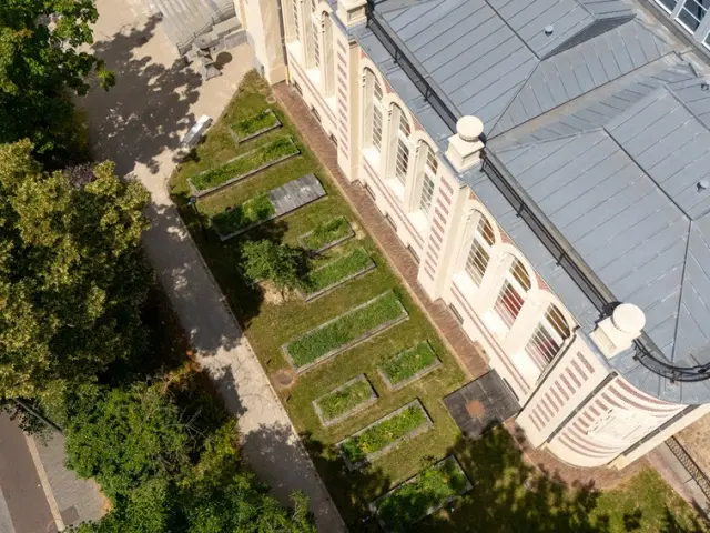 Aerial view of the Palais Rameau in Lille, showing its zinc roof and the experimental vegetable gardens lining the historic building.