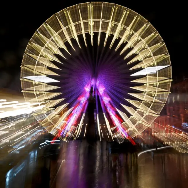 Effet lumineux artistique sur la grande roue de Lille, créant un halo coloré et mouvant.