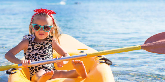 Little cute girl kayaking in the clear blue sea